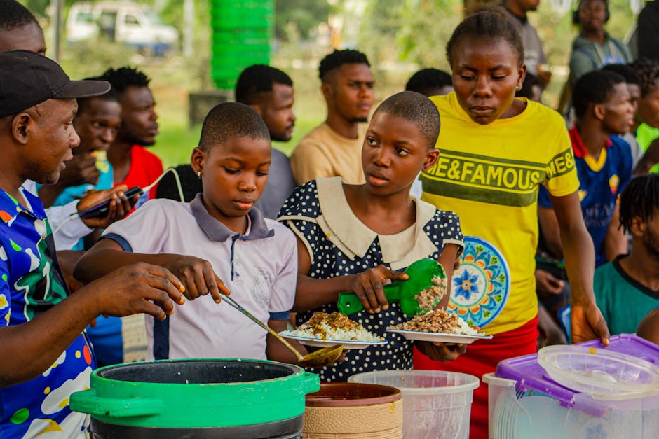 Personnes réunies en plein air partageant et préparant un repas traditionnel. Une scène culturelle dynamique.